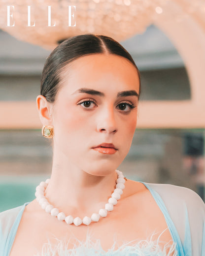 Woman wearing a paper bead pearl necklace and light blue dress with 'ELLE' branding.